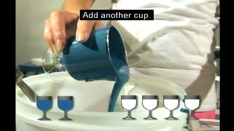 Person pouring a cup of blue liquid into a bucket. Diagram of two blue cups and four white cups on the bottom of the image. Caption: Add another cup.