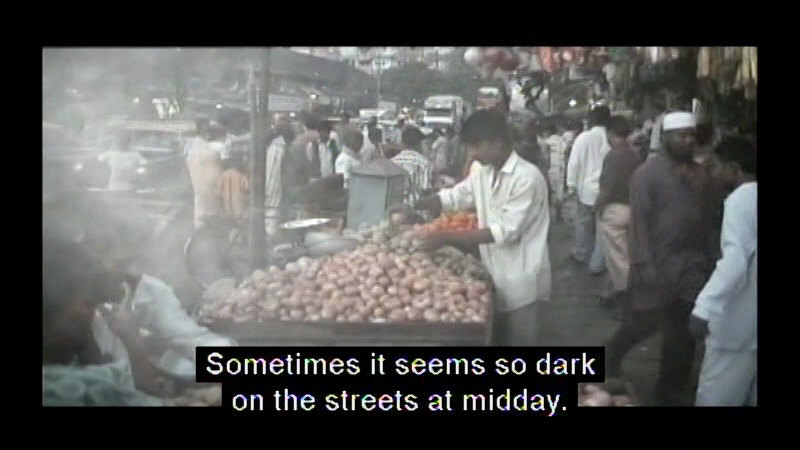 A crowded street covered in fog. Caption: Sometimes it seems so dark on the streets at midday.