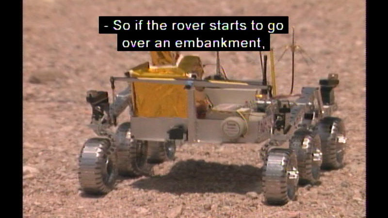 Open carriage vehicle with six wheels. Caption: -So if the rover starts to go over an embankment,