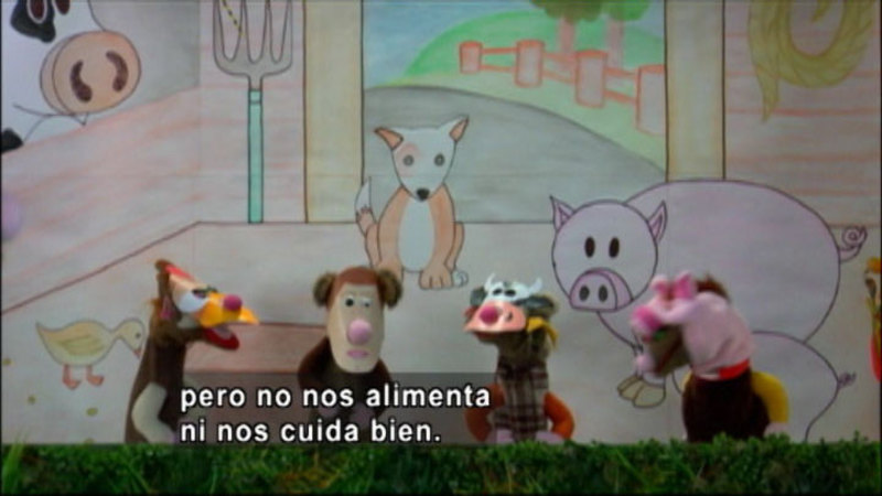 Animal puppets in front of the backdrop of a barn. Spanish captions.