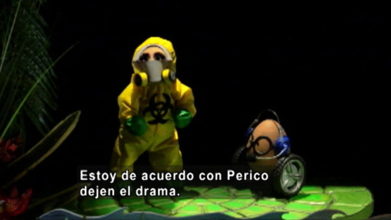Two puppets, one in a hazmat suit.  Spanish captions.