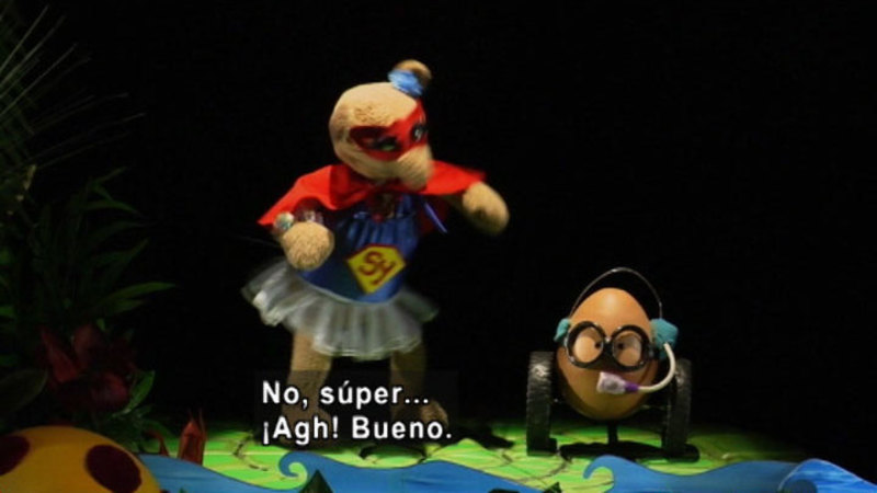 Two puppets, one wearing a superhero costume. Spanish captions.