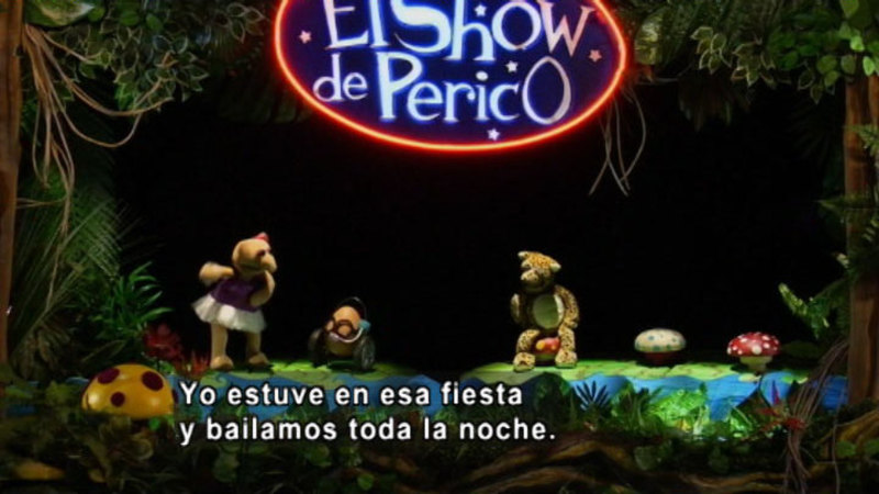 Three puppets on a stage. Spanish captions.