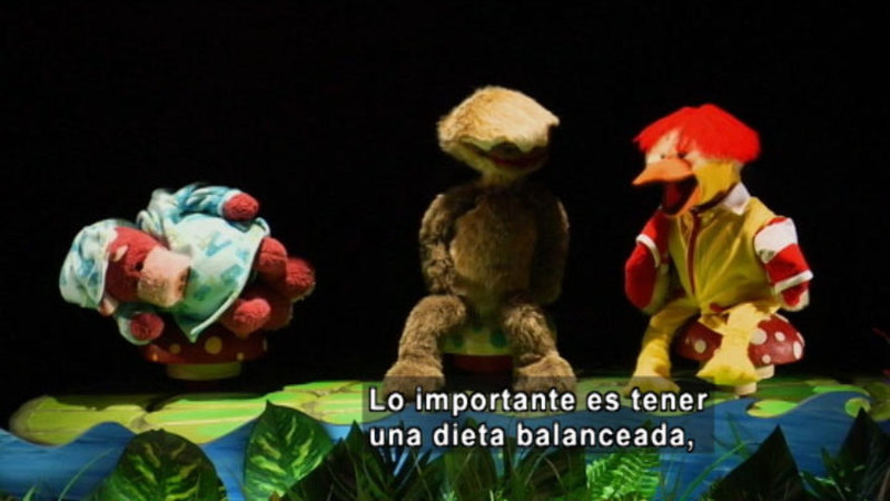 Three puppets talking by the water. Spanish captions.