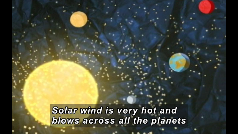 Illustration of the Sun and planets closest to it, including Earth, shedding bits of bright light. Caption: Solar wind is very hot and blows across all the planets