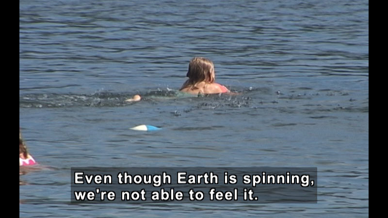 Person swimming in water. Caption: Even though Earth is spinning, we're not able to feel it.