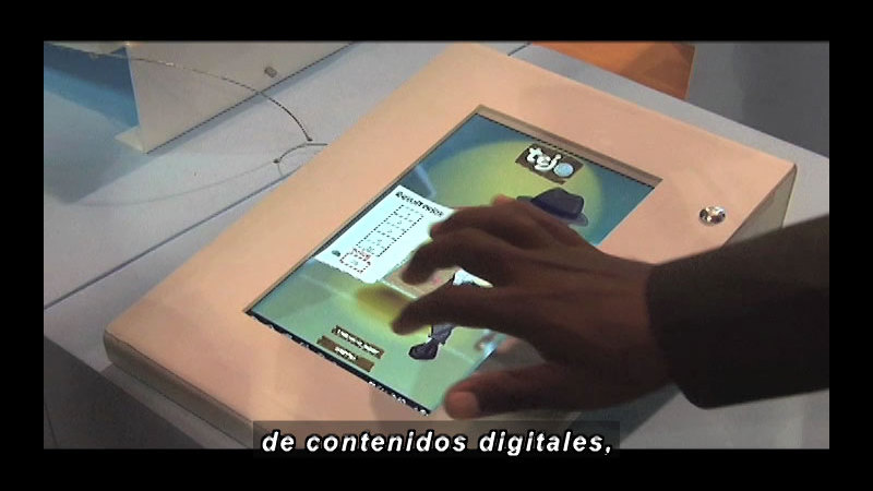 Person using a touch screen. Spanish captions.
