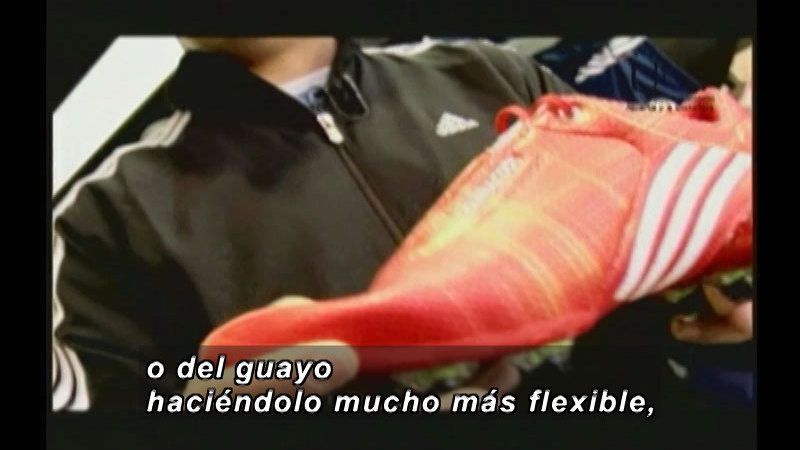 Person holding a shoe. Spanish captions.