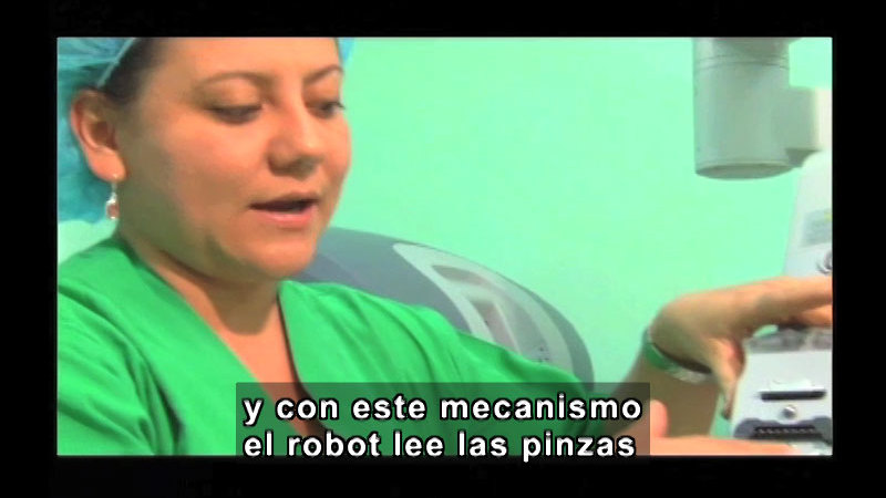 Person in scrubs handling medical equipment. Spanish captions.