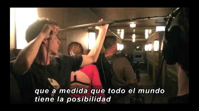 People with videography equipment. Spanish captions.