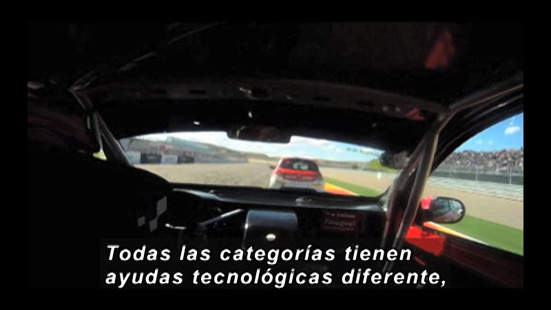 View from the cockpit of a race car. Spanish captions.