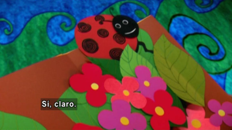 An illustrated ladybug in flowers. Spanish captions.