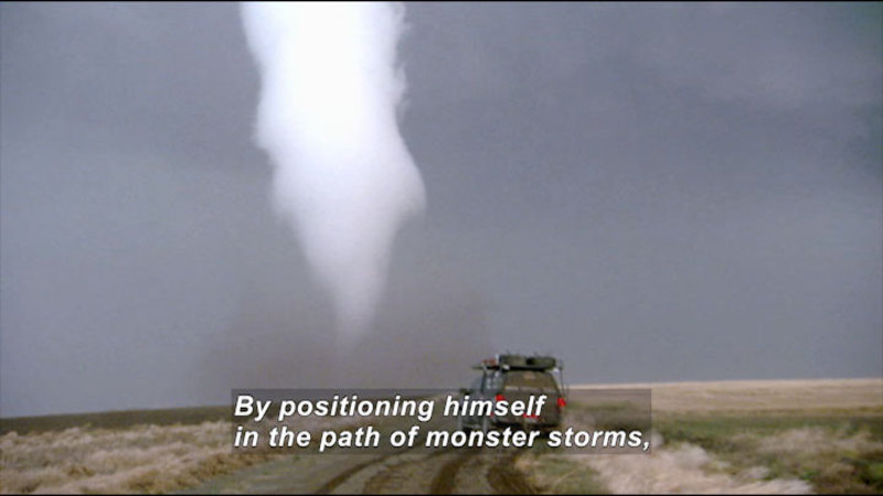 SUV stopped in the path of a funnel cloud. Caption: By positioning himself in the path of monster storms,