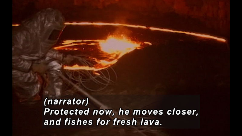 Person in a reflective heat-protecting suit crouches next to a pit of glowing lava. Caption: (narrator) Protected now, he moves closer and fishes for fresh lava.