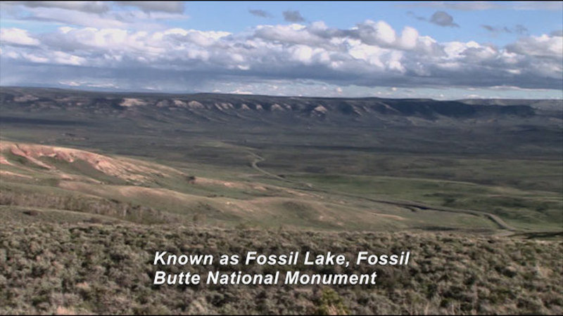 Rolling hills lead into a wide valley. Caption: Known as Fossil Lake, Fossil Butte National Monument