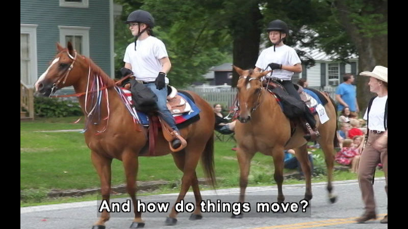 Two people riding horses while someone walks beside them. Caption: And how do things move?