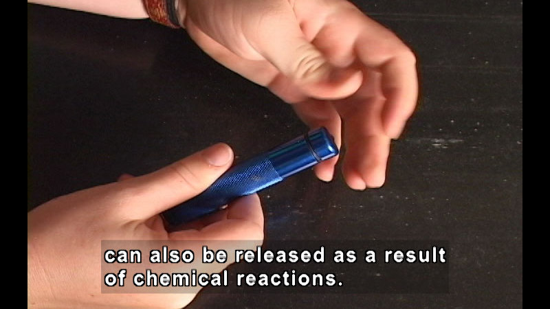Person with a blue cylindrical container in their hands. Caption: can also be released as a result of chemical reactions.