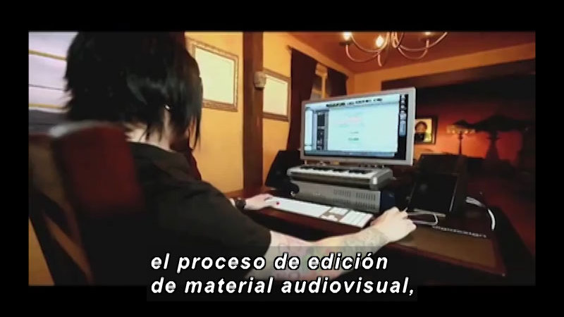 Person sitting at a computer. Spanish captions.