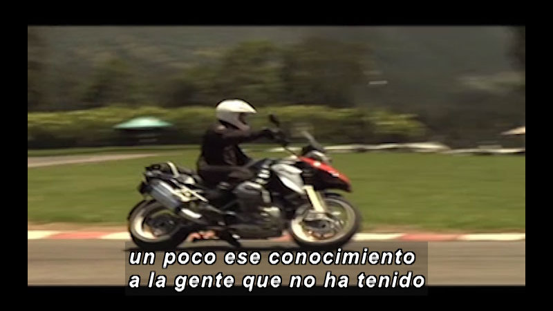 Person riding a motorcycle. Spanish captions.