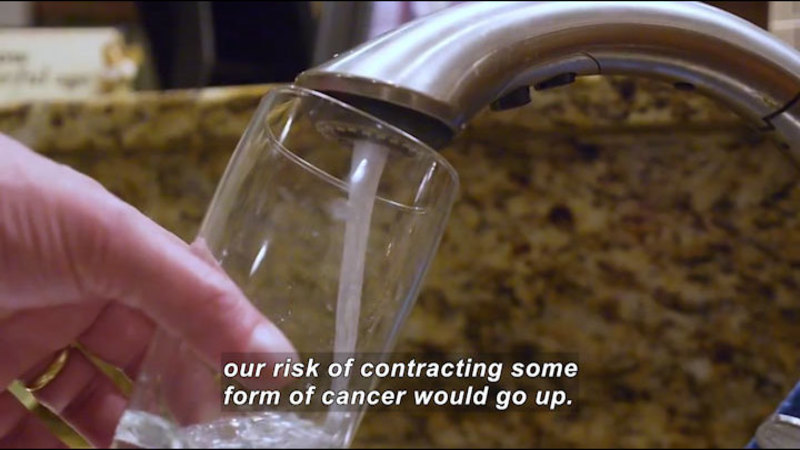 Person filling a glass from a faucet. Caption: our risk of contracting some form of cancer would go up.