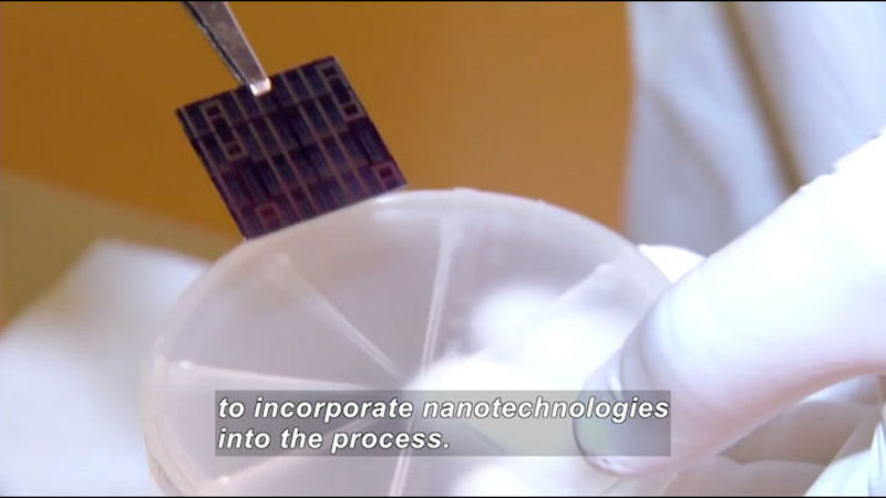 Gloved hand holding a round plastic object and putting an electronic chip into it. Caption: to incorporate nanotechnologies into the process.