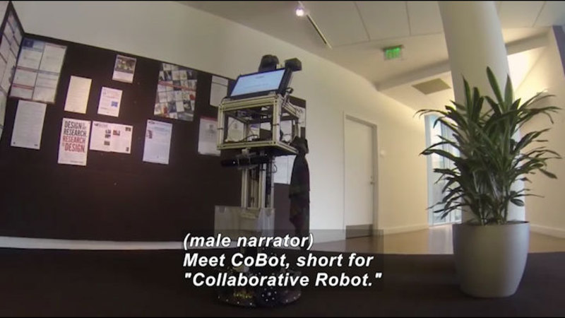 Rectangular robot with a screen at eye level. Caption: (male narrator) Meet CoBot, short for "Collaborative Robot."