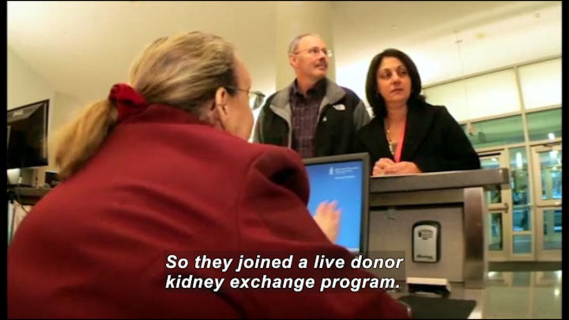 Two people standing at a counter checking in with a receptionist. Caption: So they joined a live donor kidney exchange program.