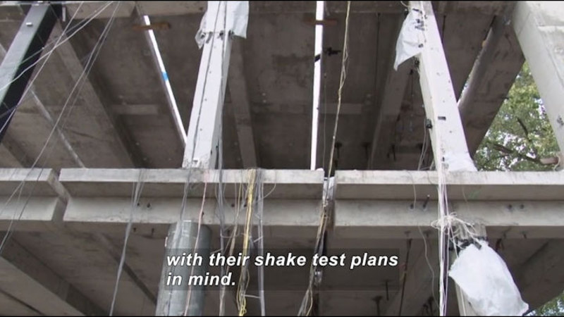 Concrete building with open walls. Wiring, cables, and other instruments are attached. Caption: with their shake test plans in mind.
