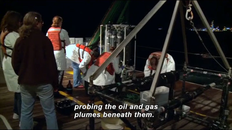 People on the deck of a ship, working on various equipment. Caption: probing the oil and gas plumes beneath them.
