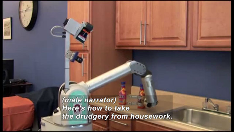 Robot with an arm moving bottles next to a sink. Caption: (male narrator) Here's how to take the drudgery from housework.