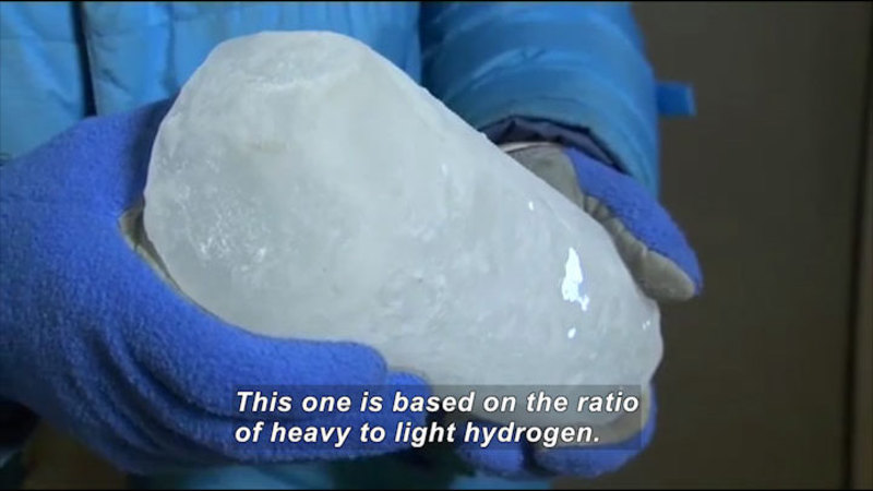 Person holding a cylindrical piece of ice. Caption: This one is based on the ratio of heavy to light hydrogen.