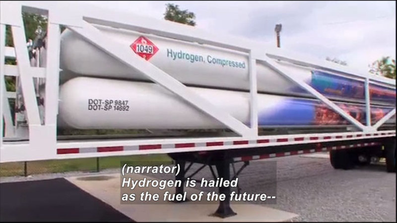 Semi-trailer with large cylindrical tanks labelled as Hydrogen, Compressed. Caption:(narrator) Hydrogen is hailed as the fuel of the future --