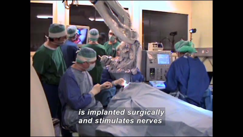 People in an operating theater with a patient on the table. Caption: is implanted surgically and stimulates nerves