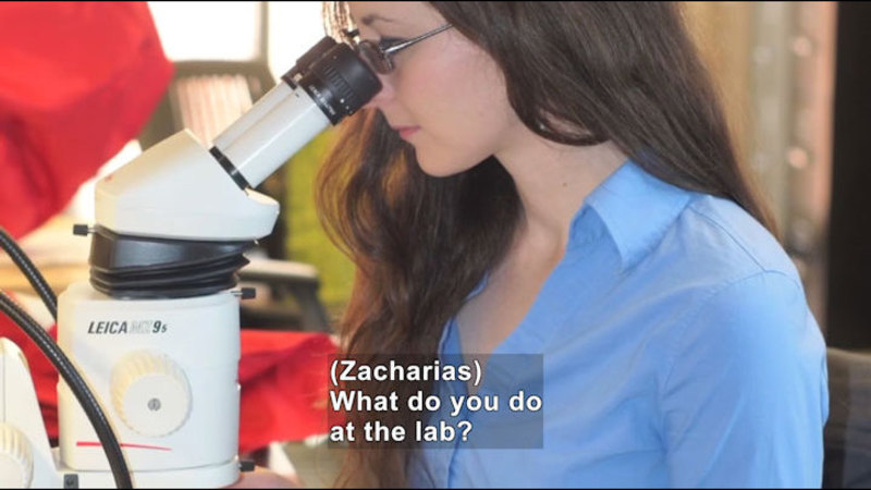 Person looking into a microscope. Caption: (Zacharias) What do you do at the lab?