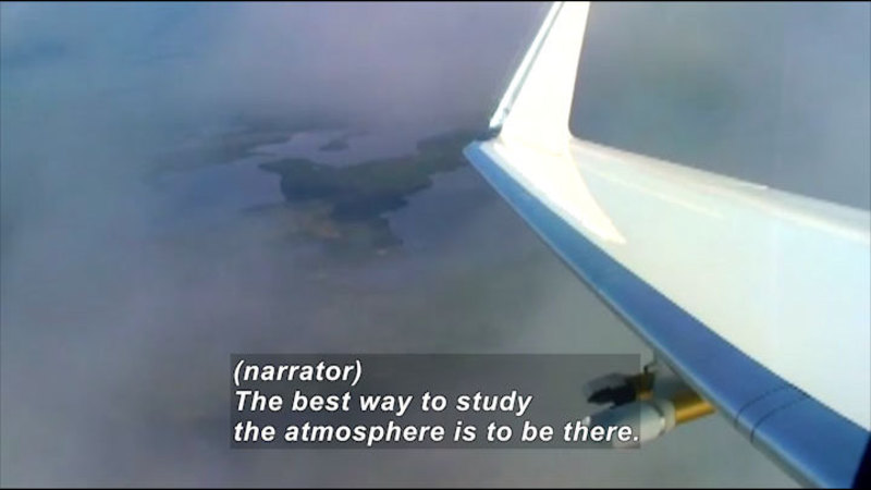 The wing of an airplane in the clouds. Caption: (narrator) The best way to study the atmosphere is to be there.