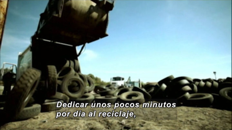 Truck dumping tires onto the ground. Spanish captions.