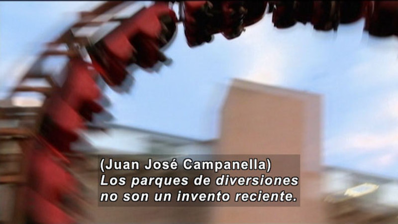 Rollercoaster with cars in the apex of loop. Spanish captions.