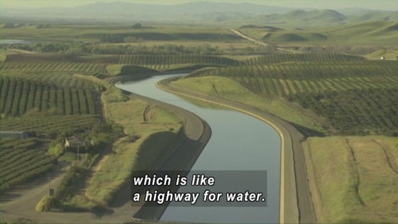 Curving river with unnaturally even banks winds through green fields. Caption: which is like a highway for water.