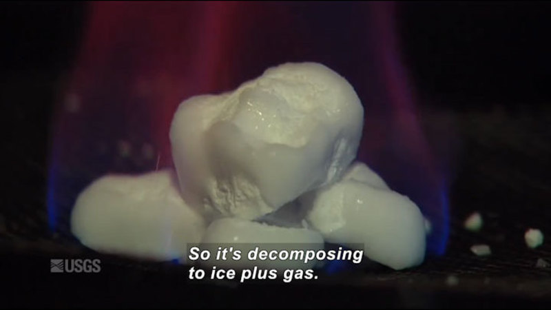 Closeup of chunks of a white substance. Caption: So it's decomposing to ice plus gas.