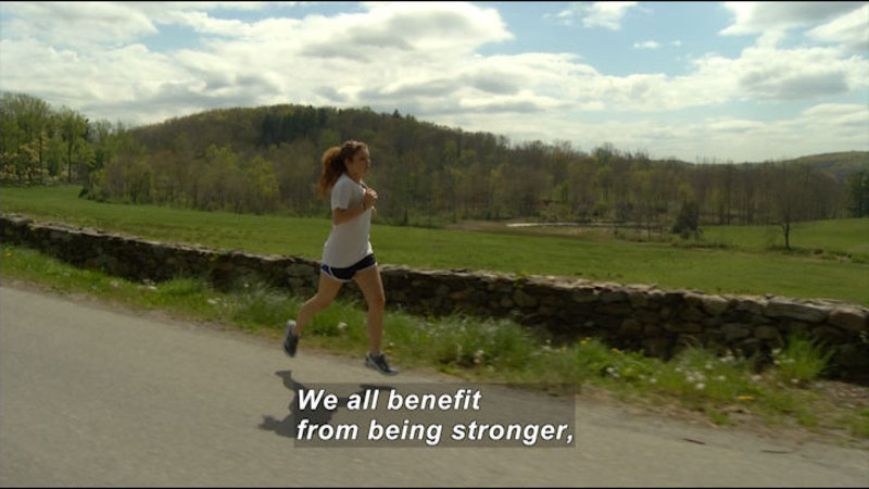 Person in shorts and a t-shirt running by a green field. Caption: We all benefit from being stronger,