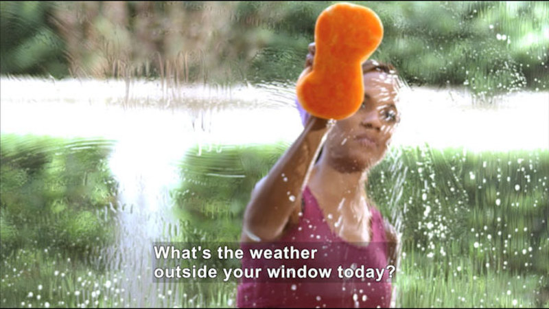 A person washing a window with a sponge. Caption: What's the weather outside your window today?