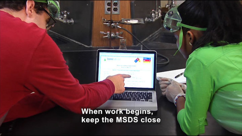 Two people looking at a laptop screen. Caption: When work begins, keep the MSDS close
