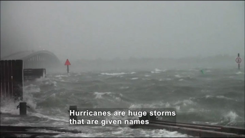Rough ocean water covering beach and surrounding areas. Caption: Hurricanes are huge storms that are given names