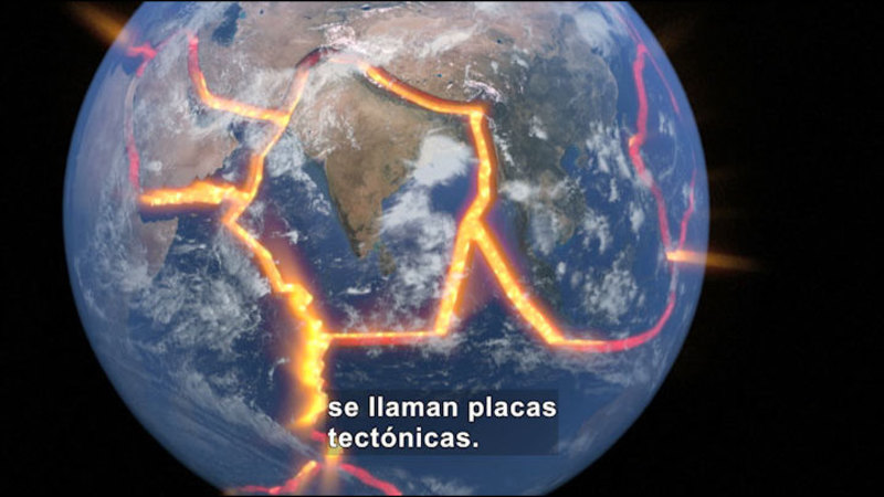 Land and ocean as seen from above with tectonic plates outlined. Spanish captions.