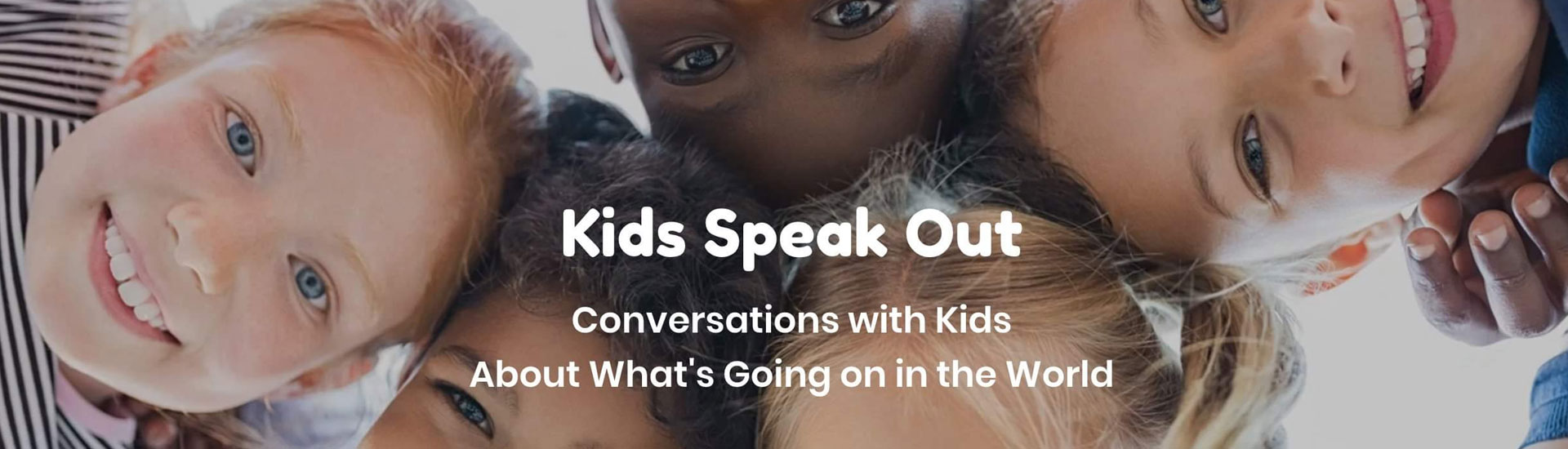 Faces of several smiling children standing in a circle, viewed from below as they look at the camera. Text: Kids Speak Out-Conversations with kids about what's going on in the world.